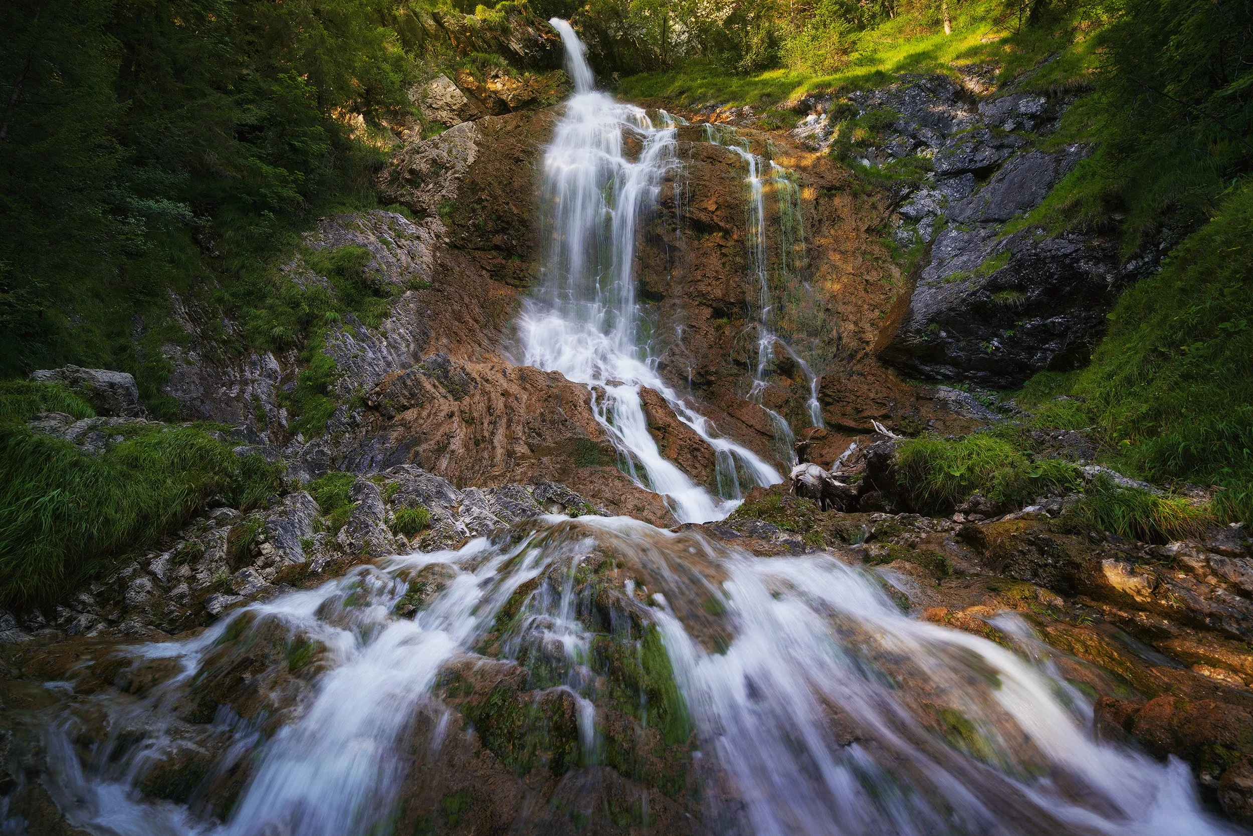 A waterfall cascading down rocks in a lush green forest.