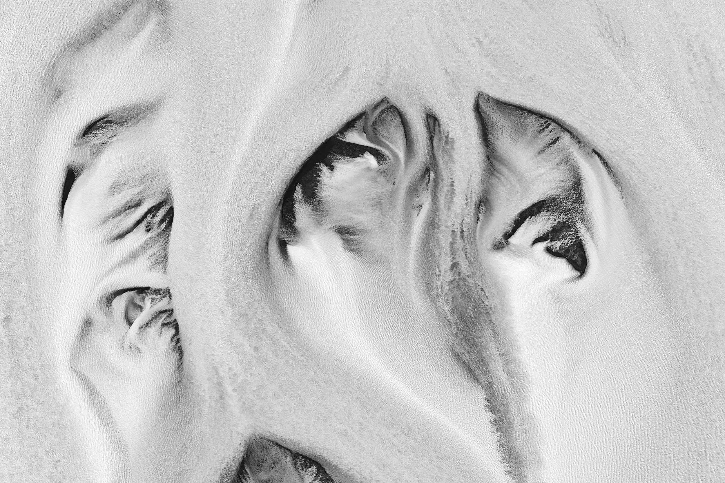 Close-up of a person's face with eyes closed, resting their face on a textured surface, depicted in black and white.