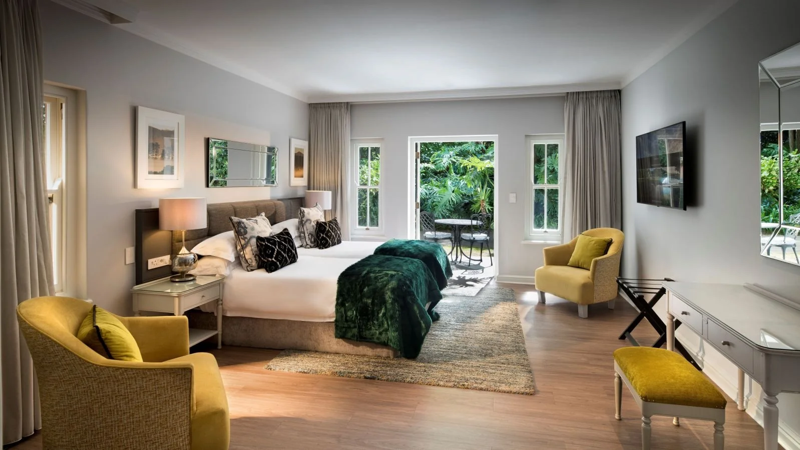 Room with a bed, yellow armchair, window views of greenery, balcony, and modern decor