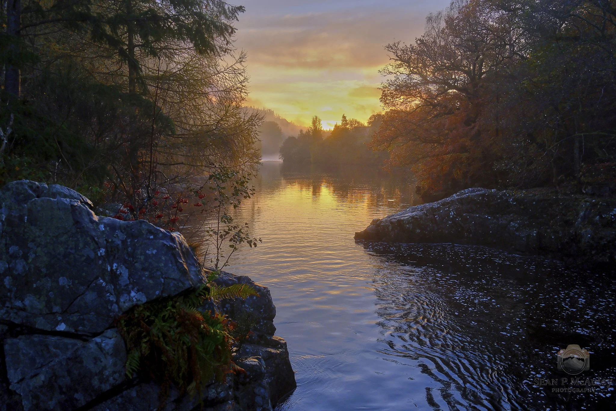 Captured at the River Garry in Killiecrankie, this fine art photograph immerses you in a moment of pure Highland tranquillity. Golden light drifts across the water as the river winds through autumn‑coloured trees and rugged stone, creating a scene th