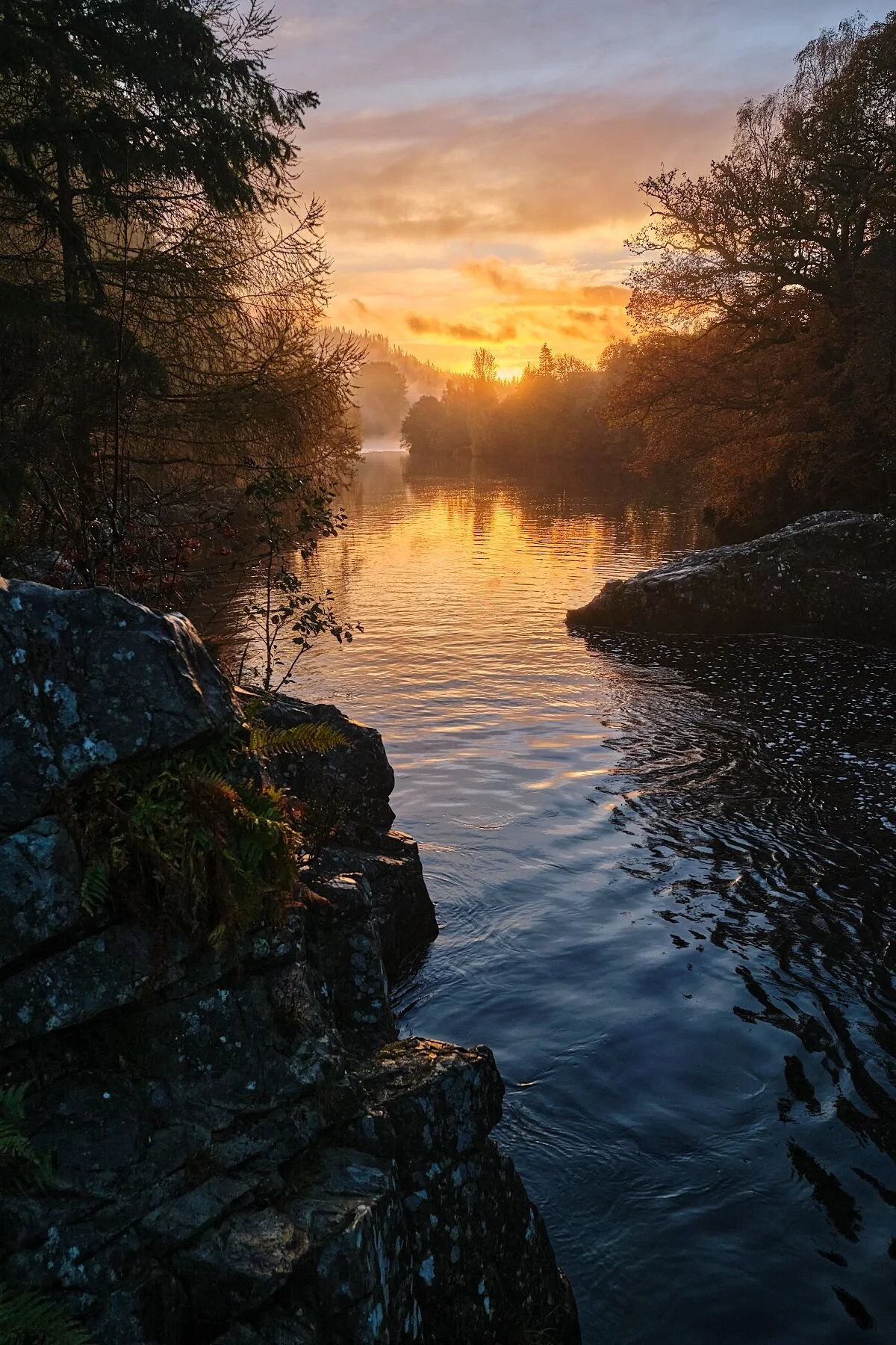 Captured at the River Garry in Killiecrankie, this fine art photograph immerses you in a moment of pure Highland tranquillity. Golden light drifts across the water as the river winds through autumn‑coloured trees and rugged stone, creating a scene th