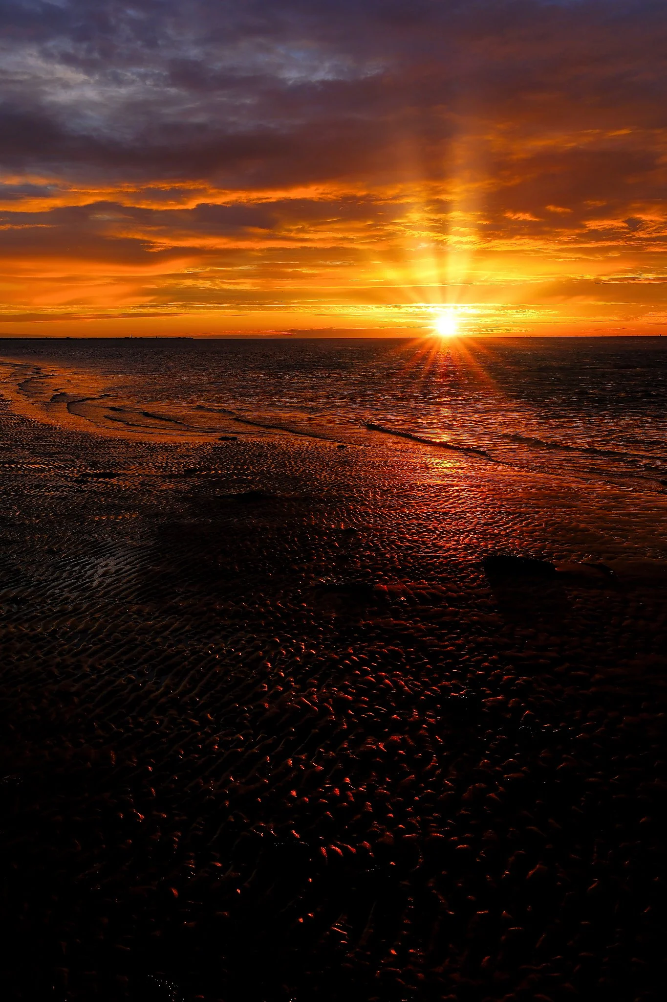 Captured at sunrise on Broughty Ferry Beach in Dundee, this photograph distils the quiet brilliance of a new day. The first light spills across rippled sand and calm water, turning the shoreline into a glowing tapestry of gold and soft violet. It’s a