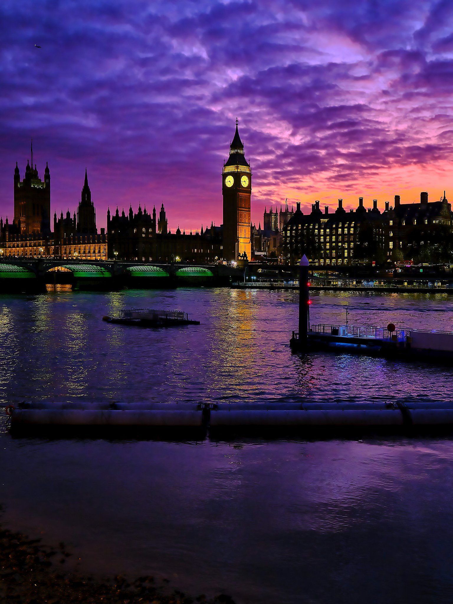Evening settles over London in a wash of deep purples and warm orange light, transforming the skyline into a scene of quiet drama. Big Ben rises above the Palace of Westminster with its familiar confidence, illuminated against a sky alive with colour