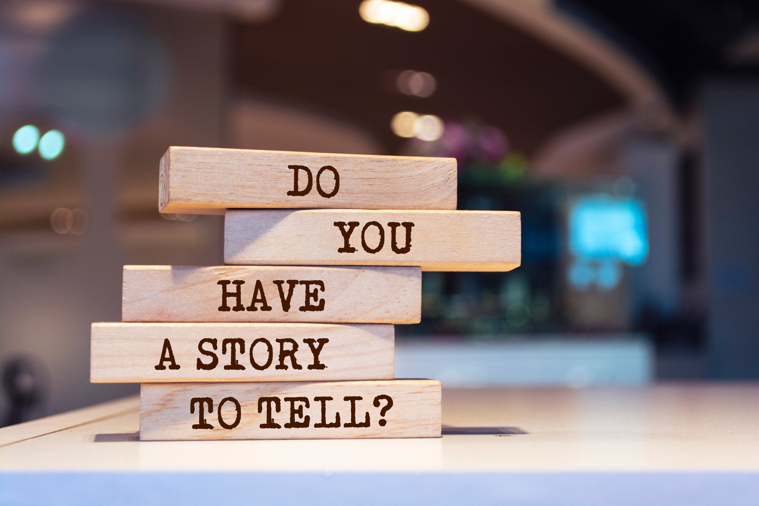 Stacked wooden blocks with the phrase "Do you have a story to tell?" written on them in black letter.