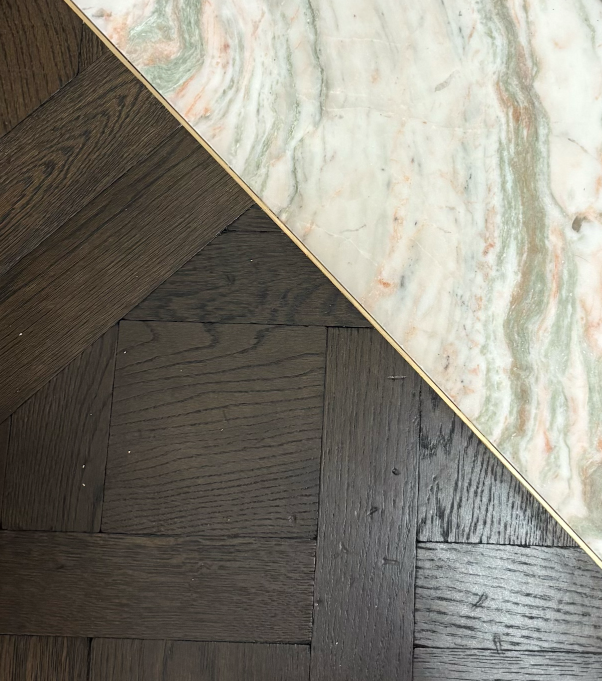 Brass trim installed between wood and marble creating subtle yet durable transition detail. 