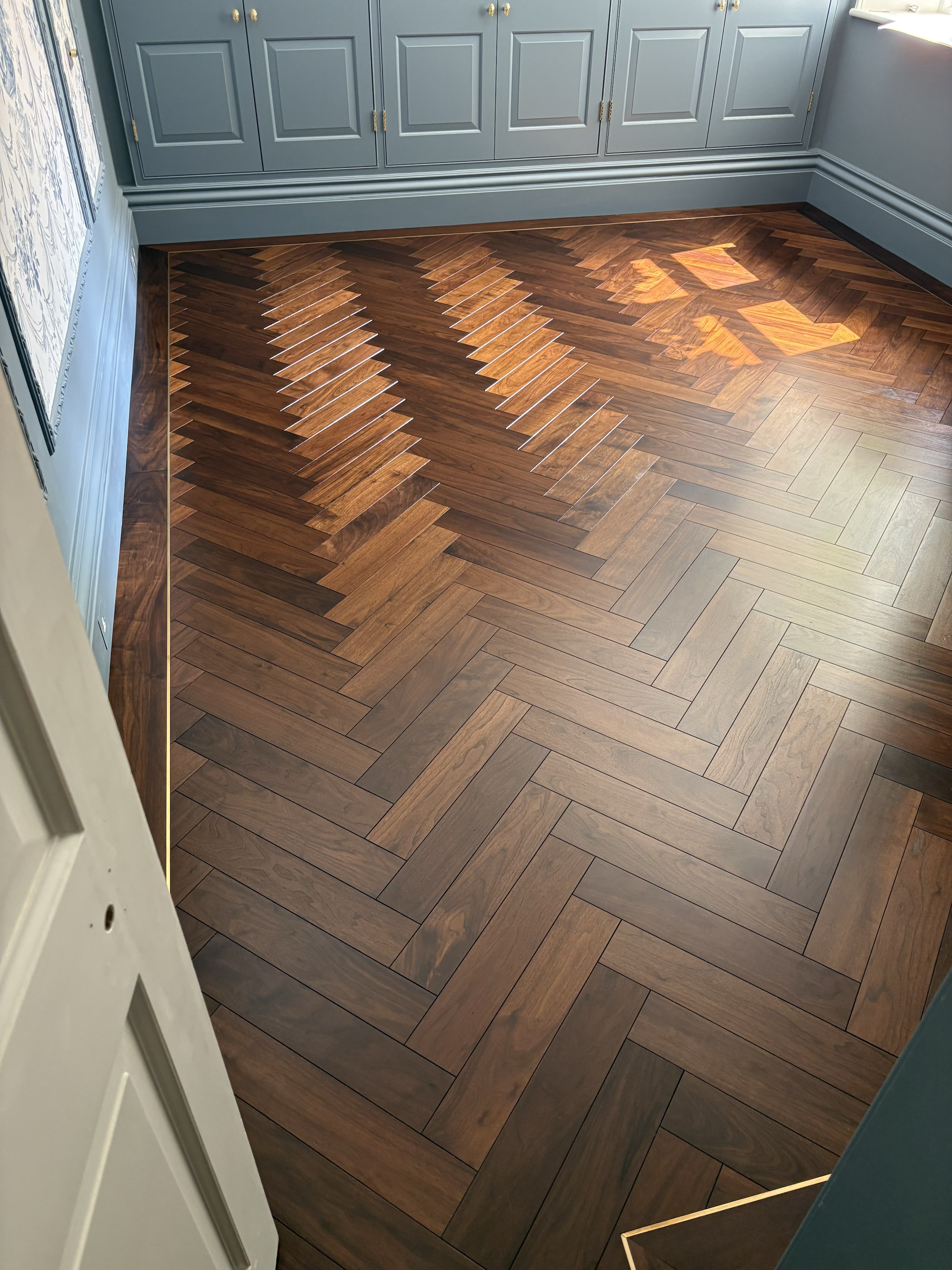 Walnut herringbone with plank border and brass inlay. 