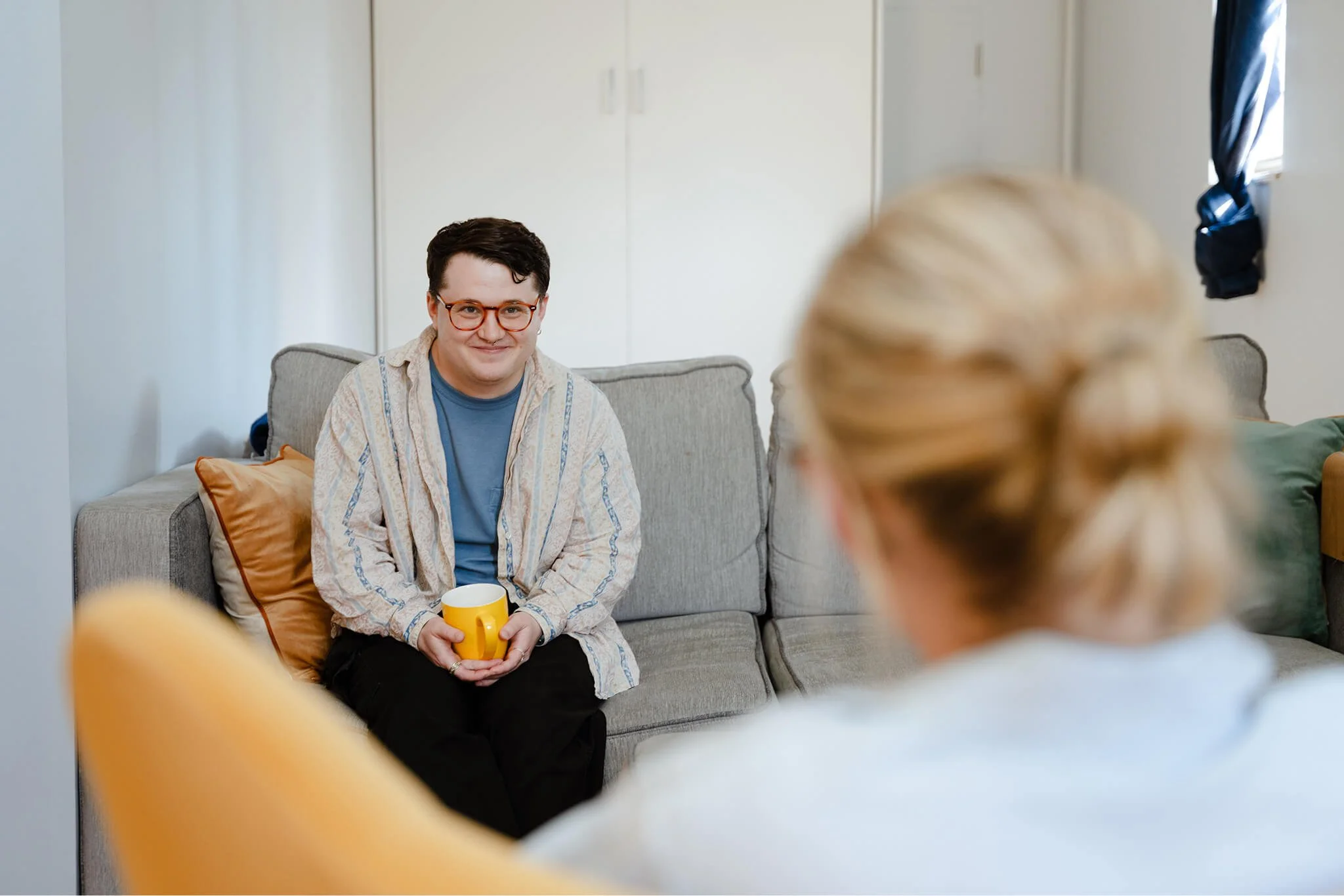 A man sitting on a couch smiling while speaking with a therapist