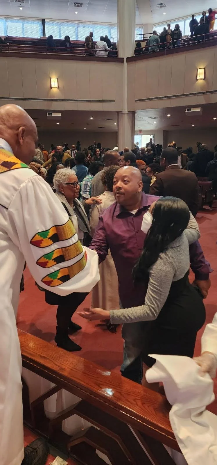 People gathered in a church or conference hall, engaging in conversation and greeting each other.