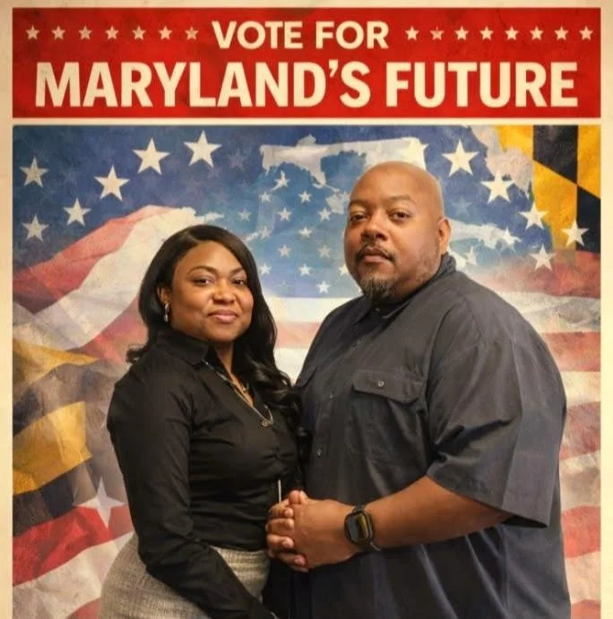 A man and woman standing in front of a political campaign poster that reads 'Vote for Maryland's Future' with a patriotic background including the Maryland state flag and the American flag. The woman has long black hair and is dressed in a black shir