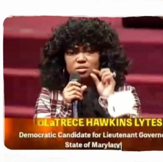 A woman with curly hair speaking into a microphone at a political event, with a banner beneath her that reads 'La'TRECE HAWKINS LYTES Democratic Candidate for Lieutenant Governor, State of Maryland.'