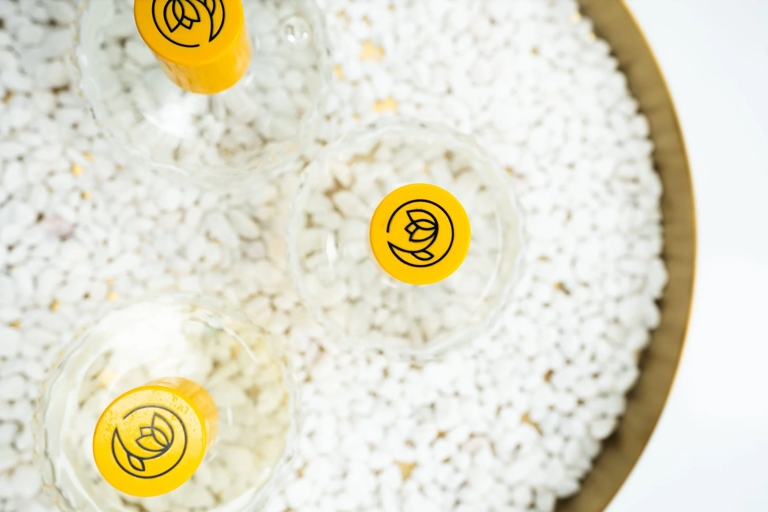 Three empty champagne glasses with yellow stickers on the bottoms, viewed from above, placed on a large tray filled with popcorn.