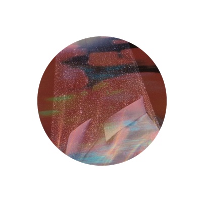 A person wearing a baseball cap and reflective sunglasses, with a pink shirt, standing in front of a red background.