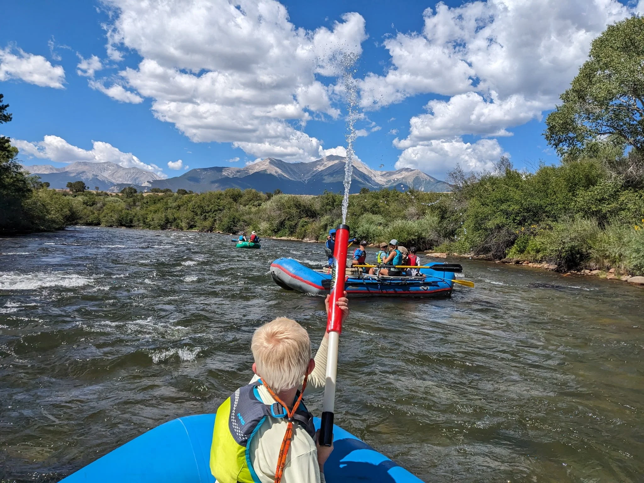 Family-friendly rafting trip on the Upper Colorado River with kids splashing water between rafts under mountain views