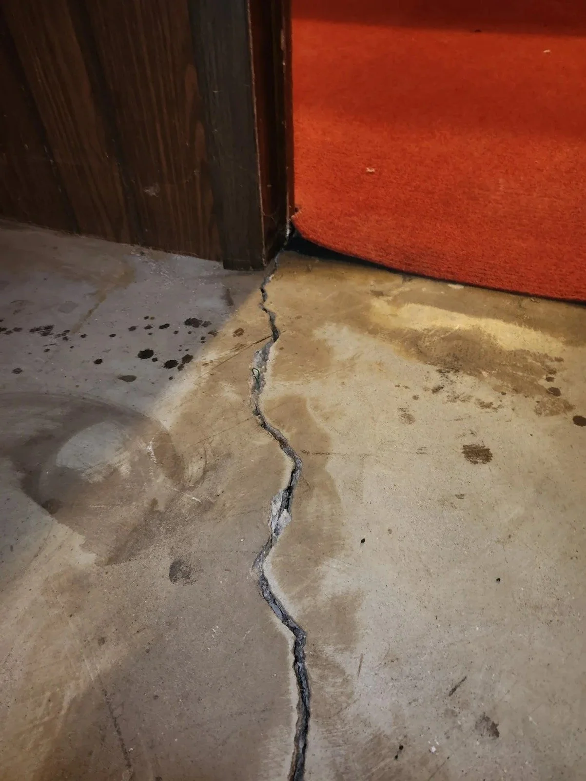 Wide slab cracks correlating with foundation wall cracks are an indication of settlement. Review for sloping floors.