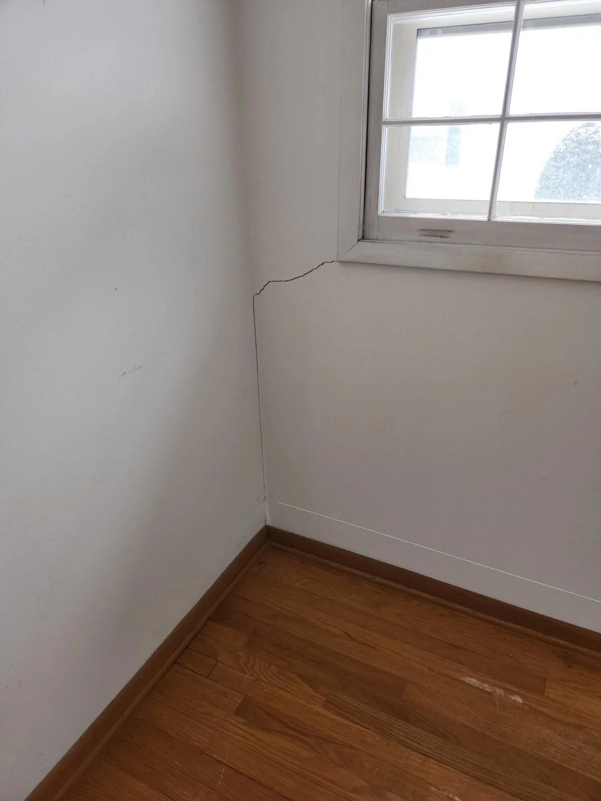Upstairs: sloping floor and a racked window opening above the settled wall.