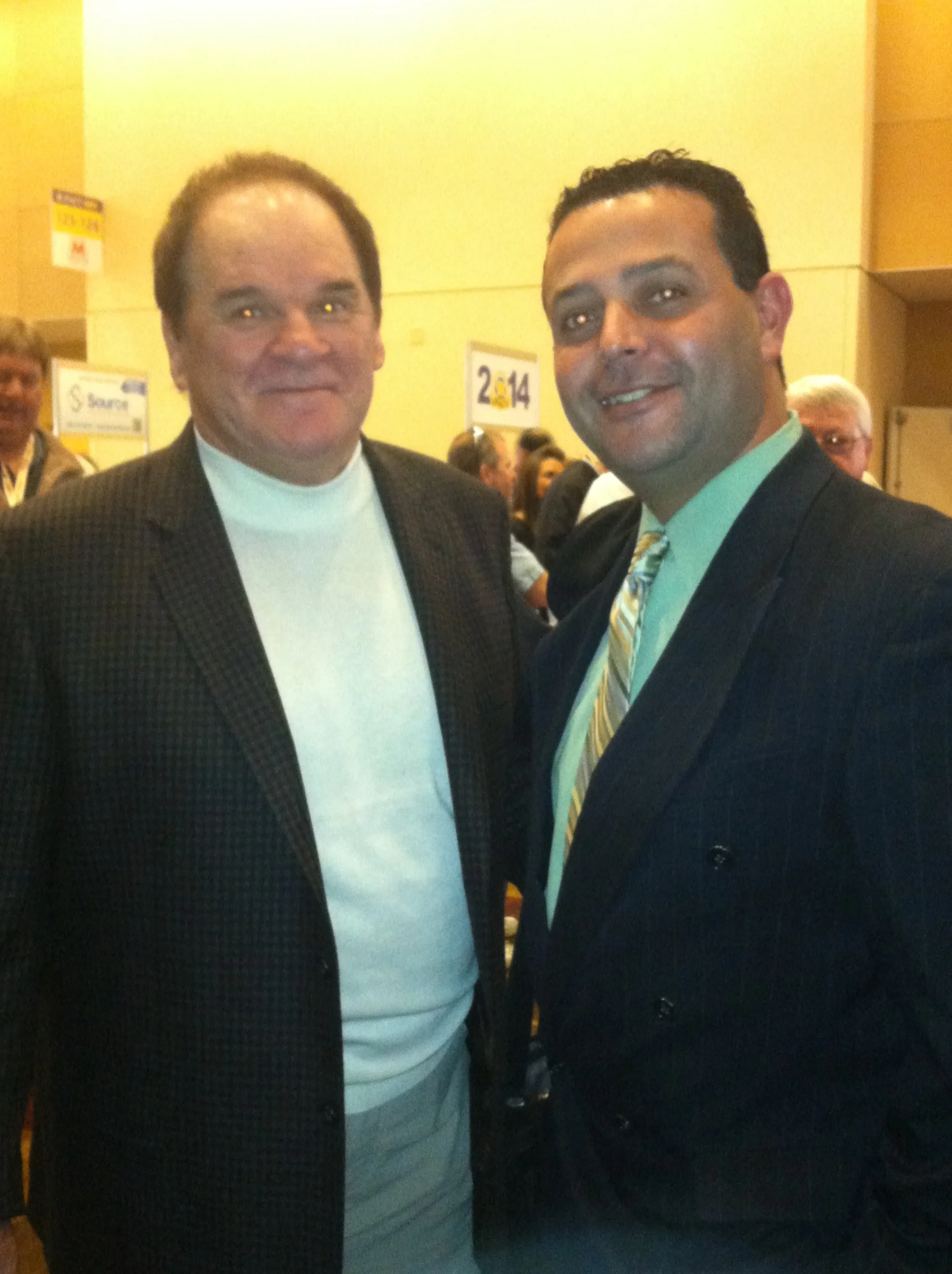 Two men in suits posing for a photo at an indoor event.