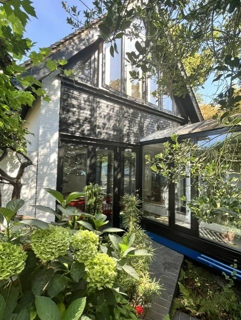 Bridge structure with black timber cladding and exterior joinery redecorated in Sadolin Superdec Obsidian, carefully finished around glazing, trims and surrounding landscaping features.