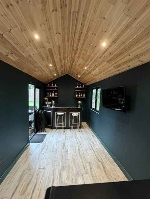Fully decorated garden room in Sandon, Chelmsford, combining a home office and bar area with Dulux Heritage Mallard Green walls and a natural timber vaulted ceiling.