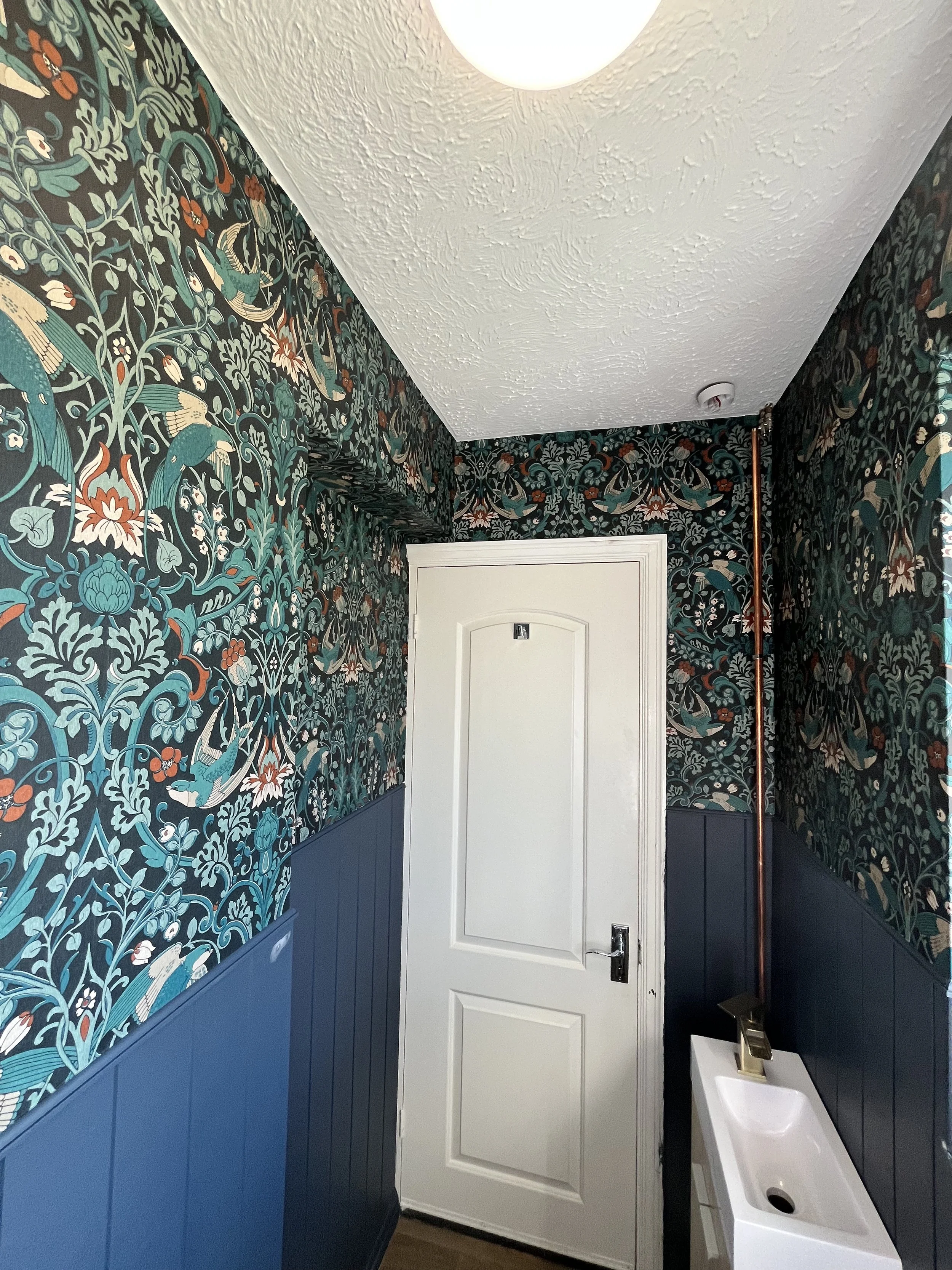wallpapered cloakroom with blue panelling and white door in Maldon Essex