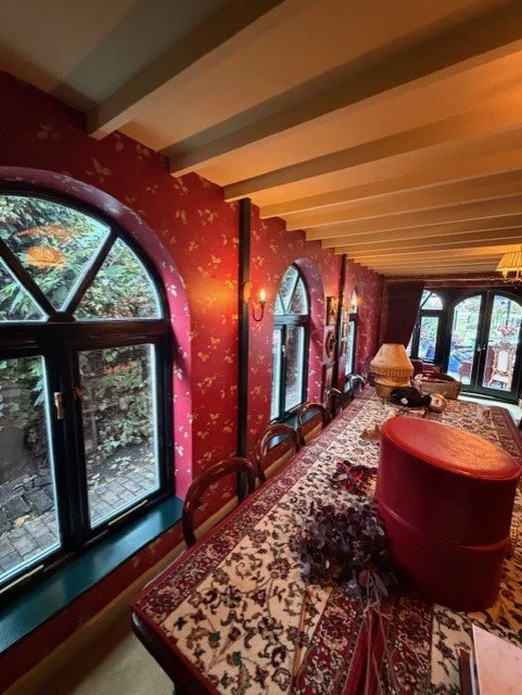 The dining area following a full redecoration, with decorative patterned wallpaper, freshly painted ceiling beams and dark green window frames complementing the traditional features of the room.