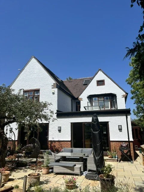 Rear elevation exterior decorating project in Colchester, Essex, featuring freshly painted white render, black facia and soffits, and burnt orange exterior joinery. Carefully prepared and finished by Bergman Decorations using durable exterior coating