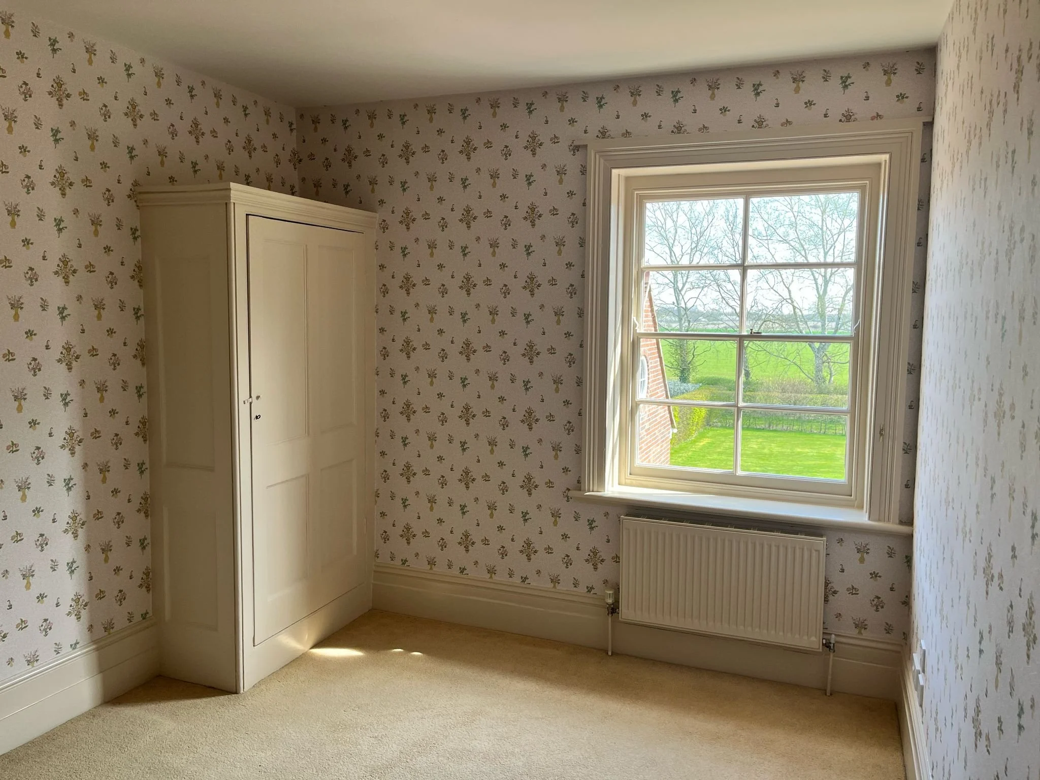 bedroom with patterned wallpaper freshly painted ceiling and woodwork in Maldon Essex