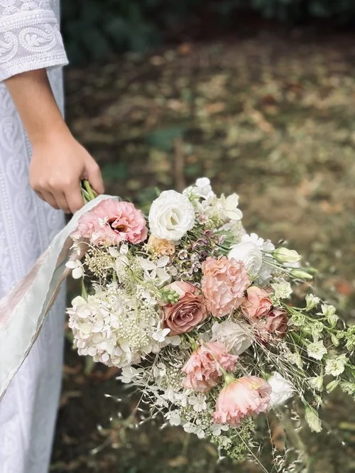 Person holding a cascading bouquet of pink and white flowers