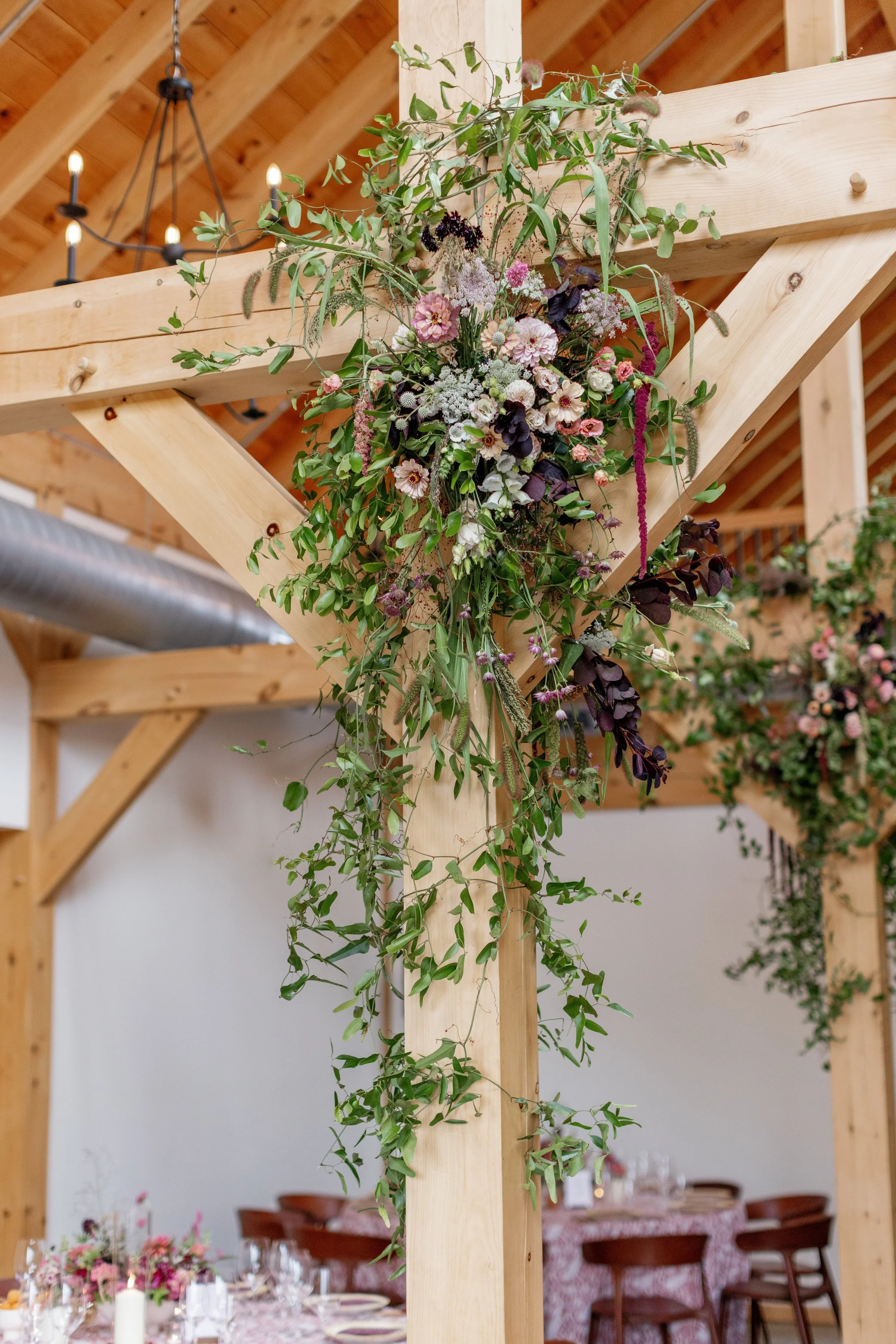 Wooden beams decorated with hanging floral arrangements in an event space.