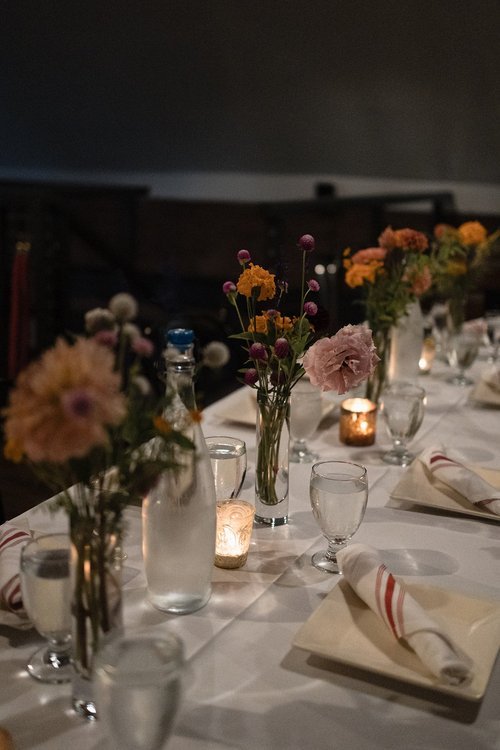 Decorated dining table with flower arrangements and candles at a dimly lit event