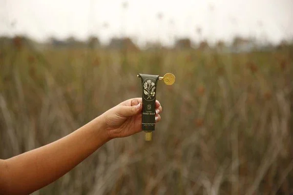 My Neighbor's Skincare Manuka Honey Hand Balm Wild Bergamot Model holding tube.jpeg