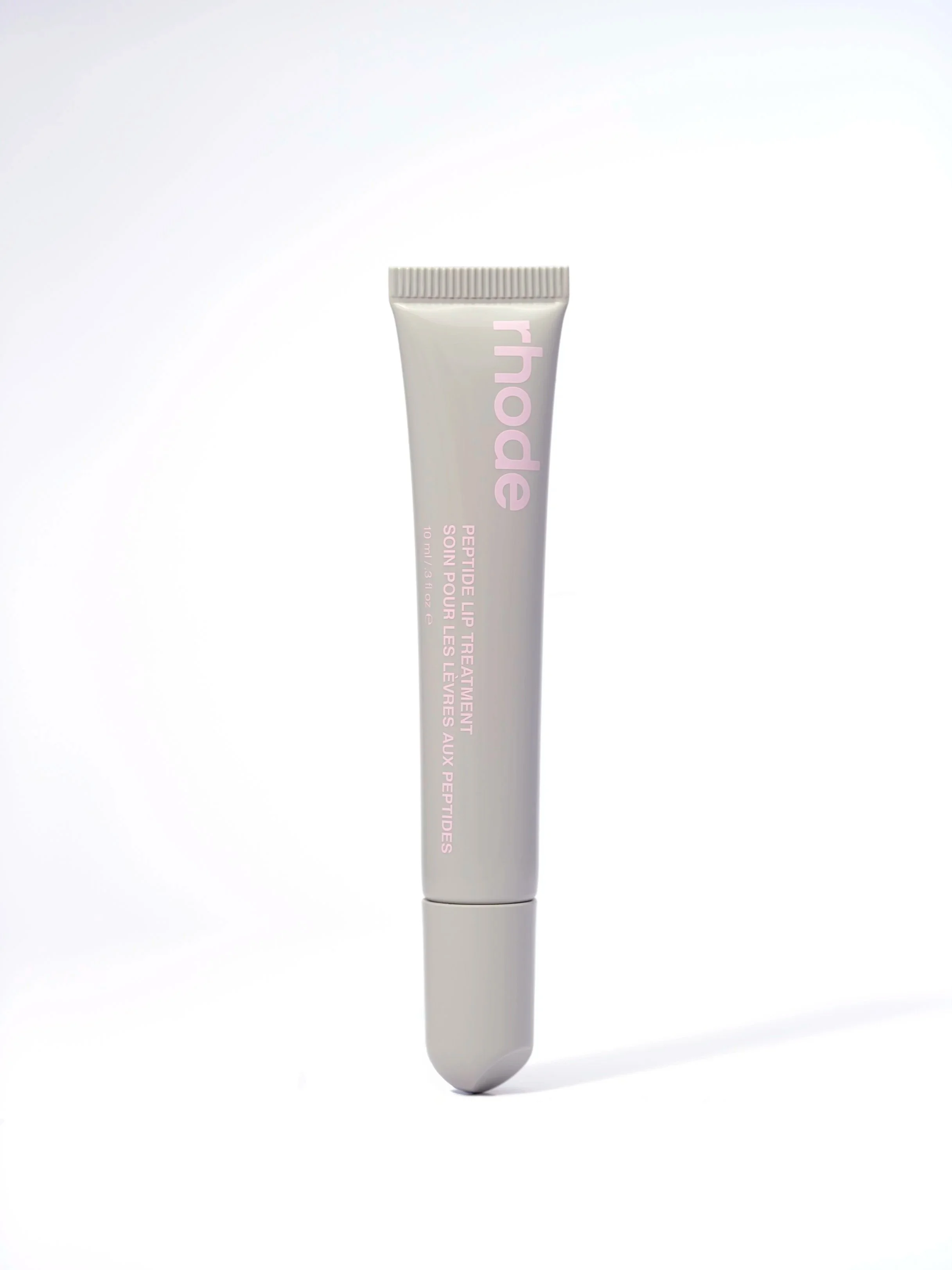 A tube of Rodan + Fields Peptide Lip Treatment with a pink and white label, standing upright against a light background.