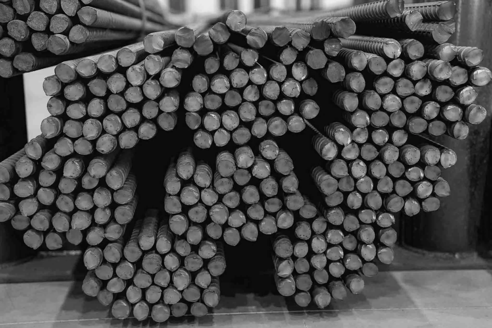Stacks of steel reinforcement bars arranged horizontally in a warehouse or construction site.