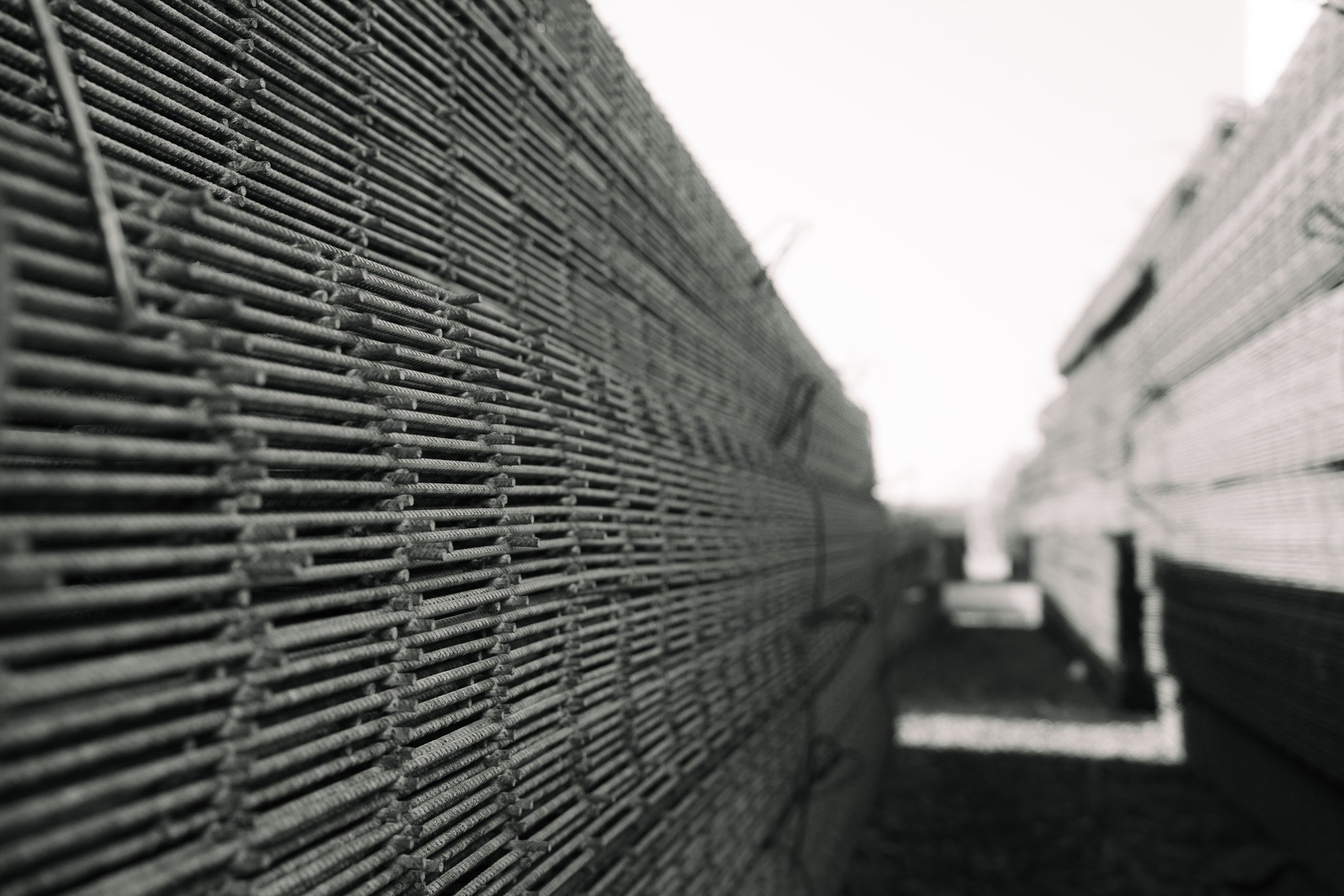 Close-up of stacks of metal rebar used for construction, arranged in parallel rows.