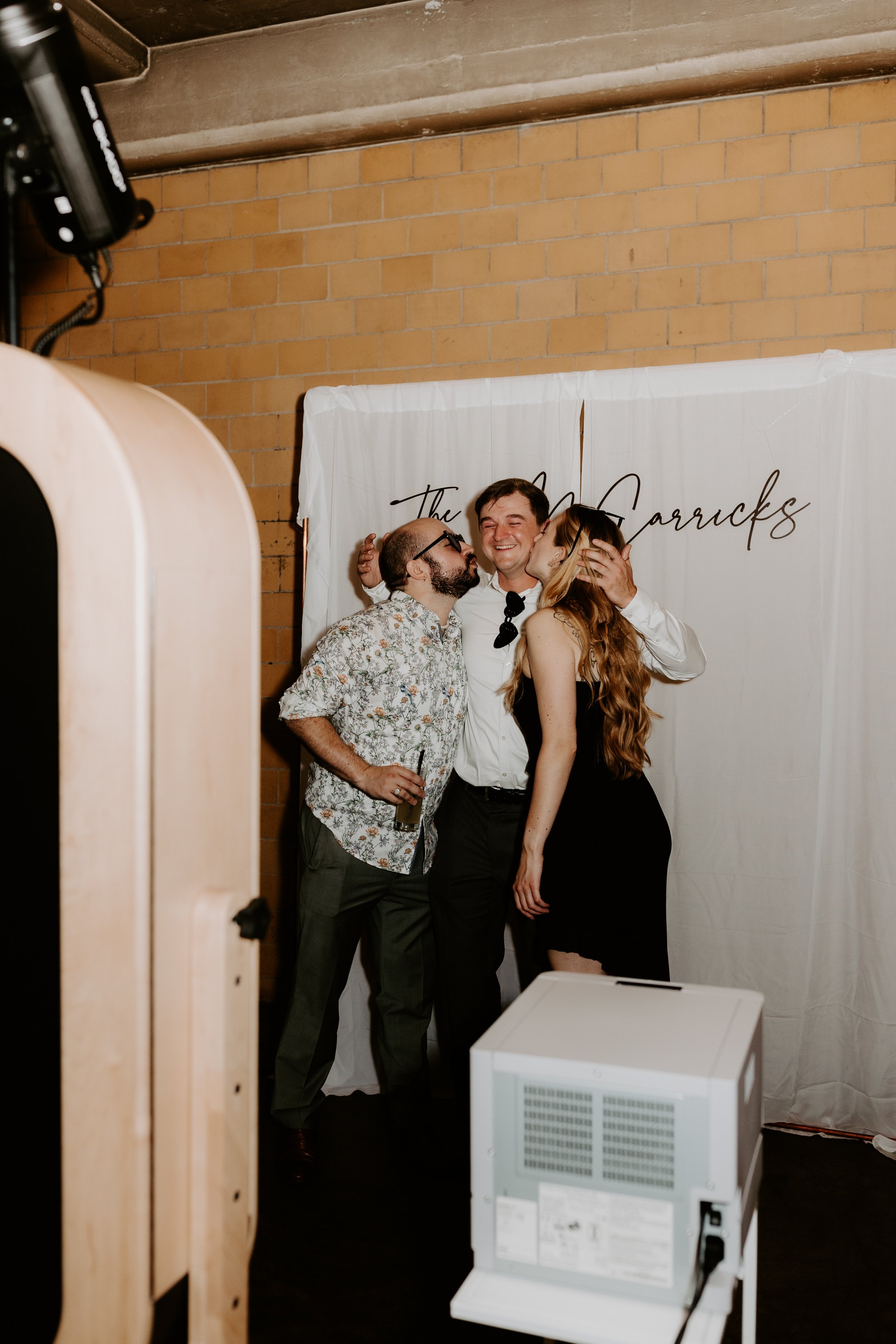 Wedding guests using elegant photo booth with white backdrop