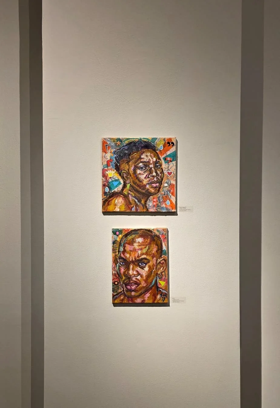 Two colorful portrait paintings of Black women displayed on a gallery wall.