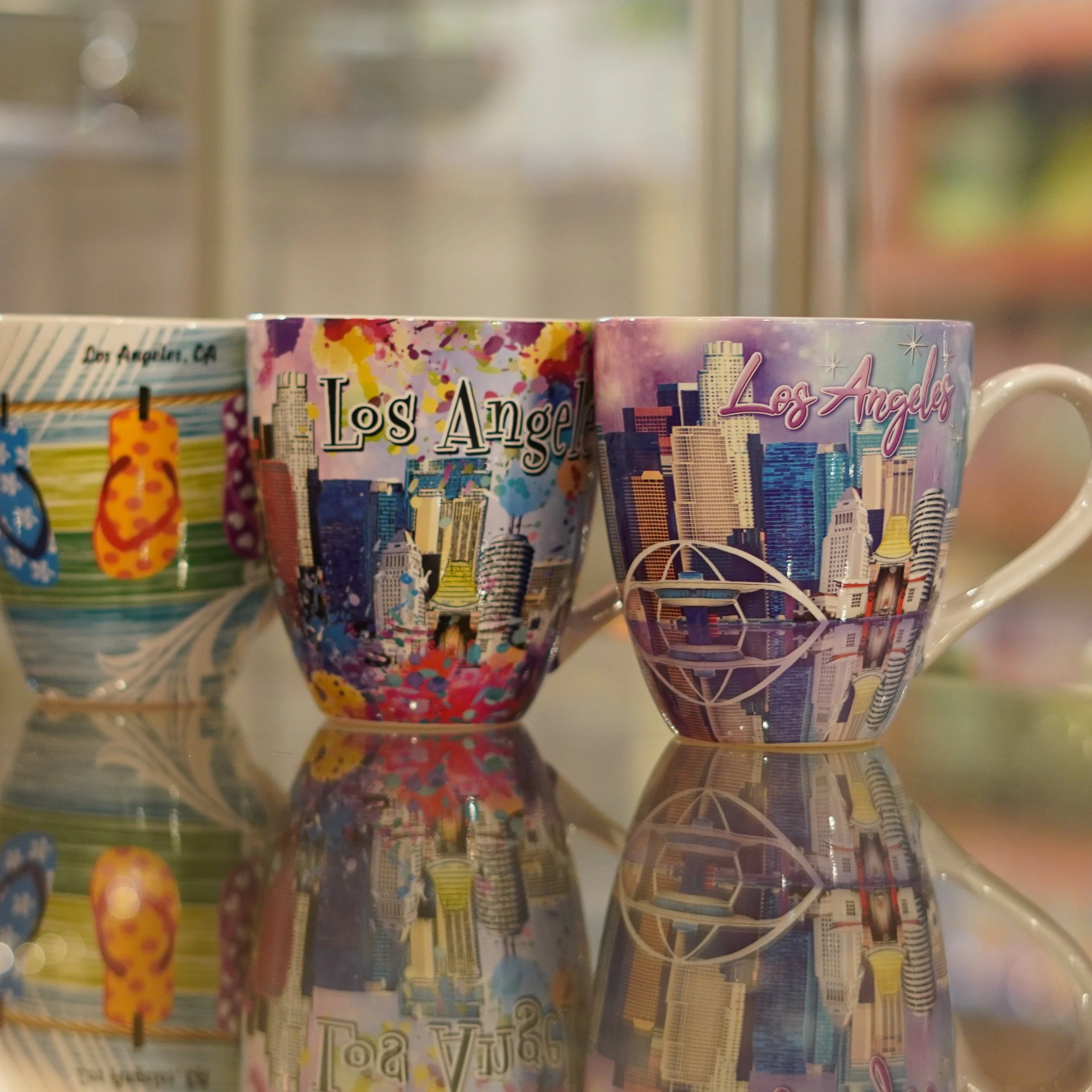 Los Angeles souvenir mugs featuring iconic landmarks available at The French Kitchen Convenience & Liquor Store.