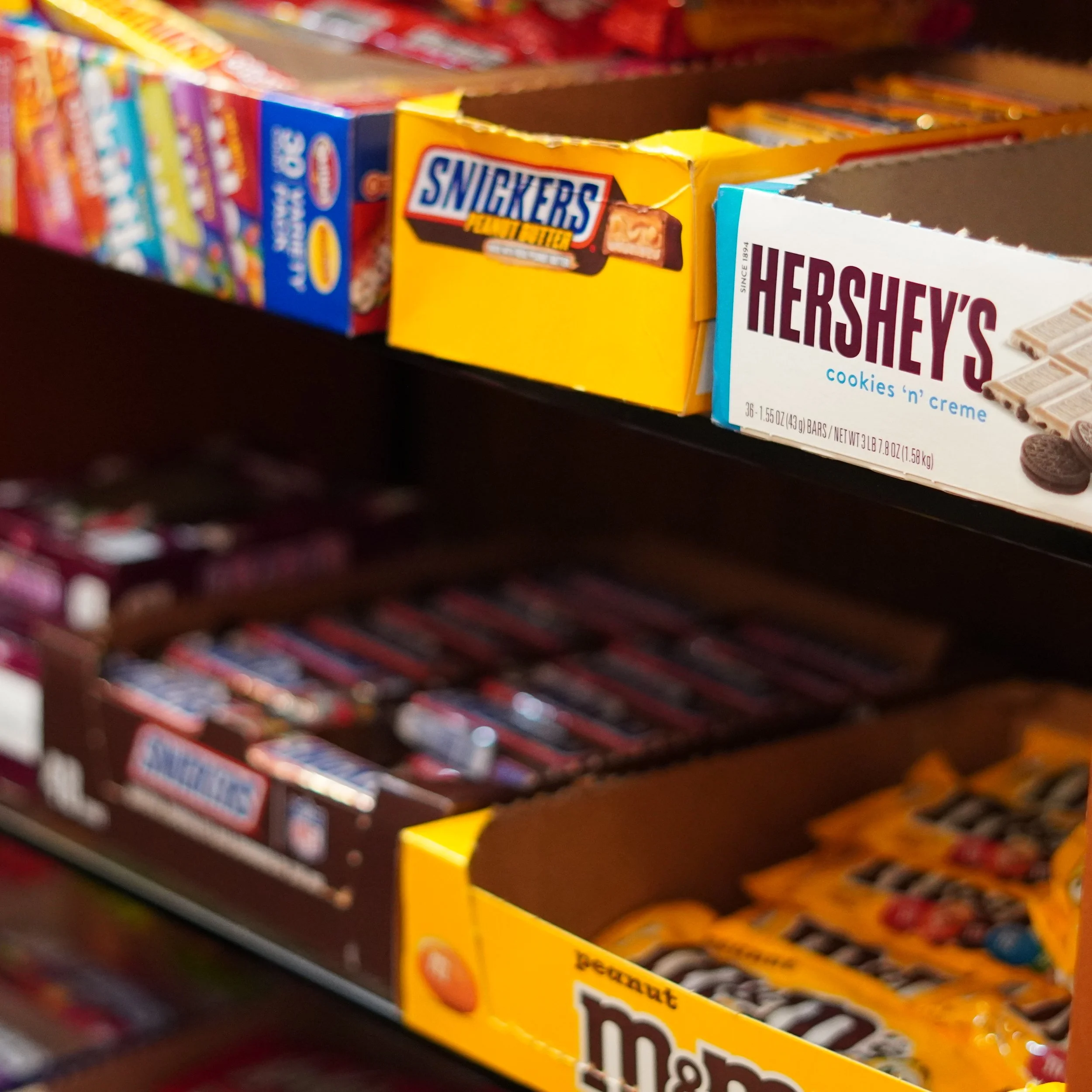 Various candy bars including Snickers, Hershey's cookies 'n' creme, and M&M's on a store shelf on 4th floor westin bonaventure