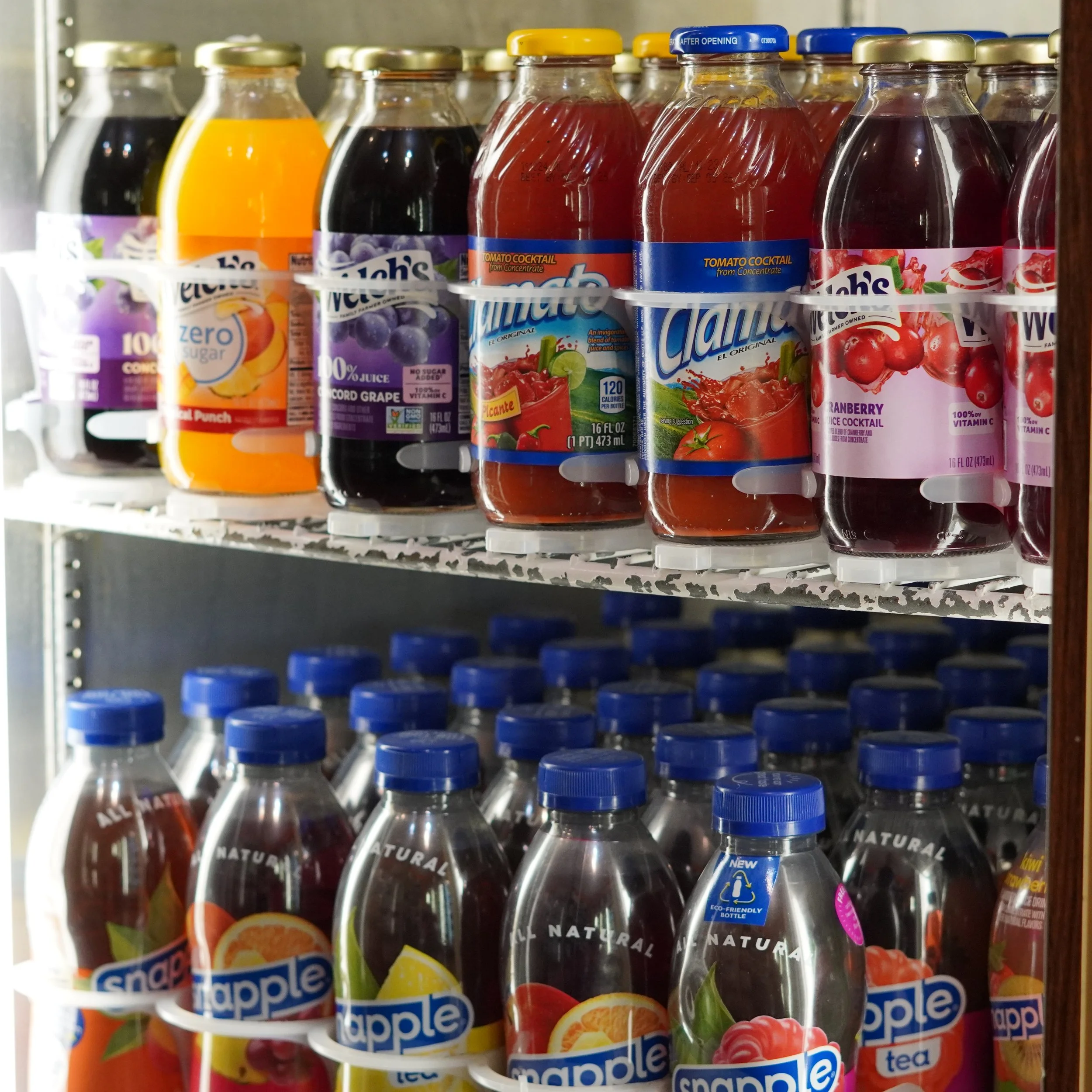 Refrigerator shelf filled with bottles of flavored drinks, including juice, fruit punch, and fruit-flavored tea, with some bottles having blue caps and colorful labels.
available on 4th floor Westin Bonaventure