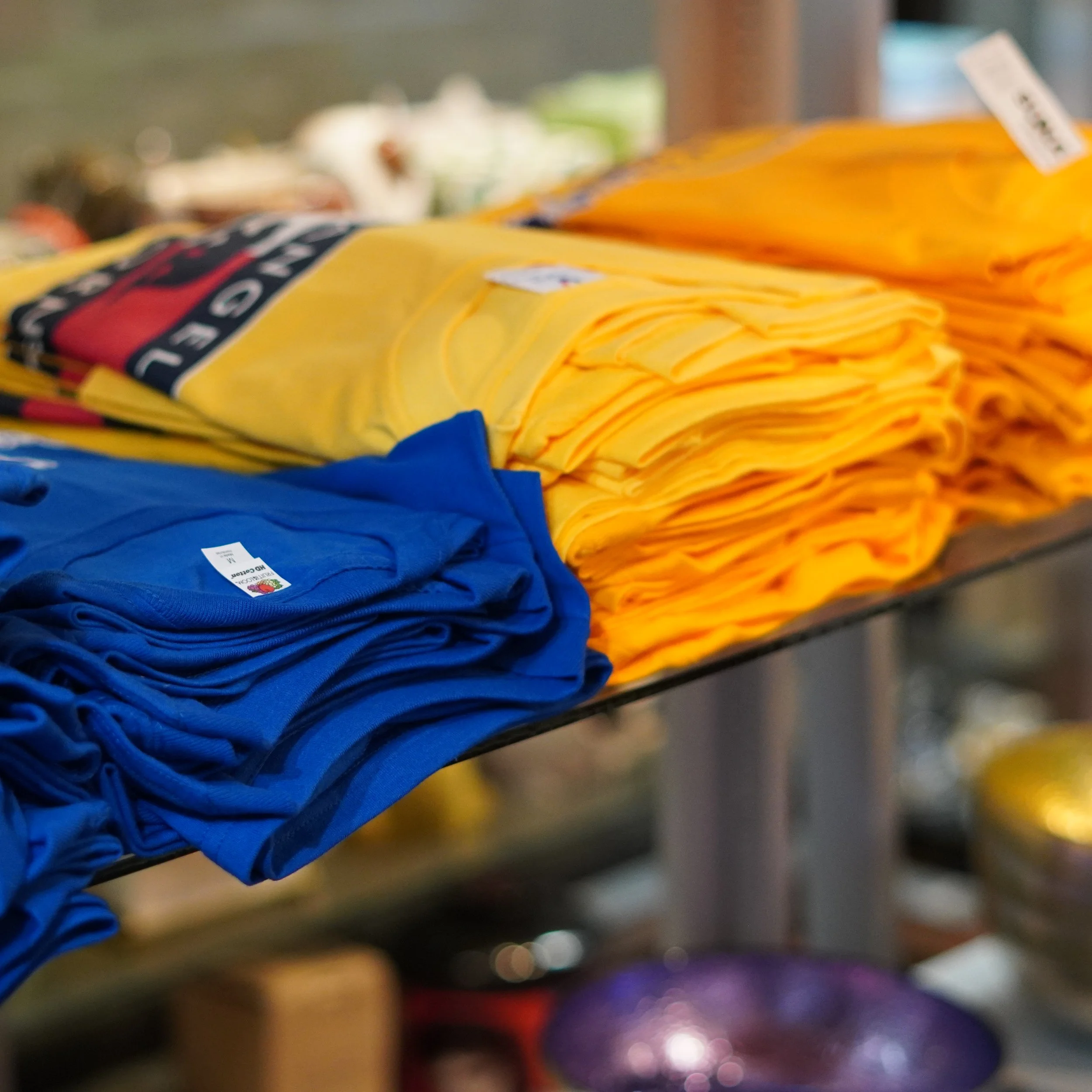 folded souvenir T-shirts in blue and yellow on display at The French Kitchen Convenience & Liquor Store