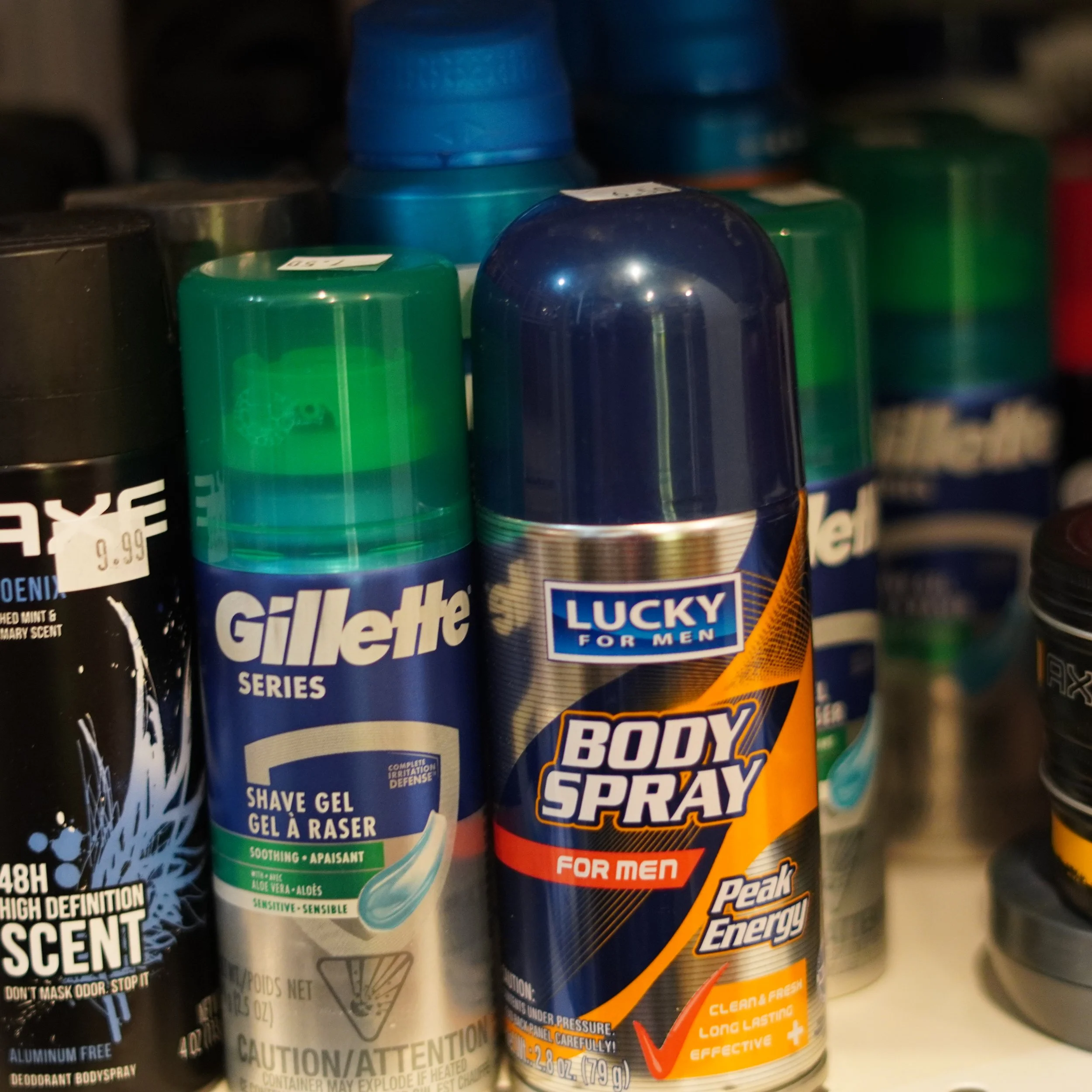 A shelf with various men's grooming products, including Gillette shave gel and Lucky Body Spray for men, with some items partially visible.