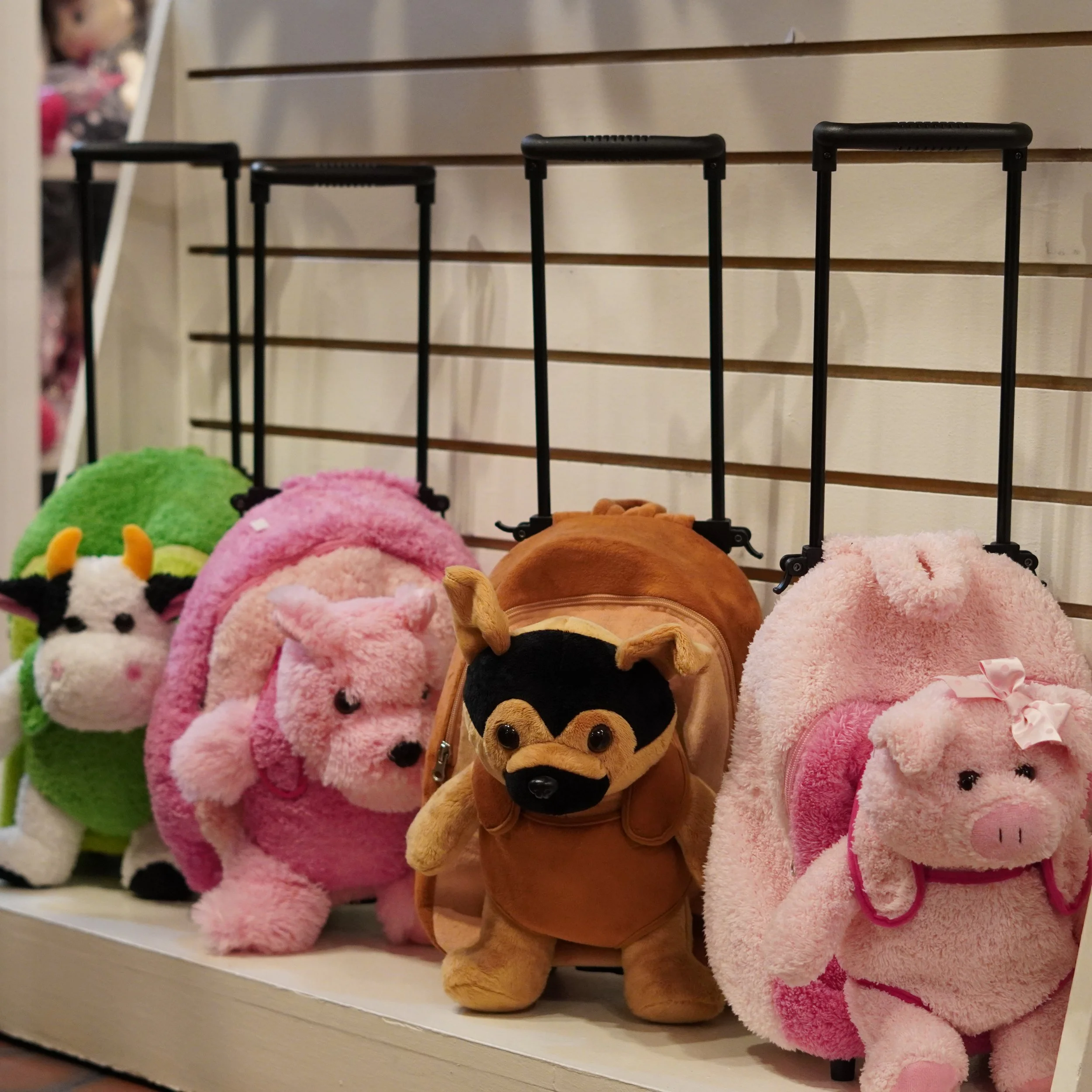 Display of plush animal backpacks shaped like a cow, pig, dog, and sheep on a store shelf of The French Kitchen one-stop shop inside The Westin Bonaventure 