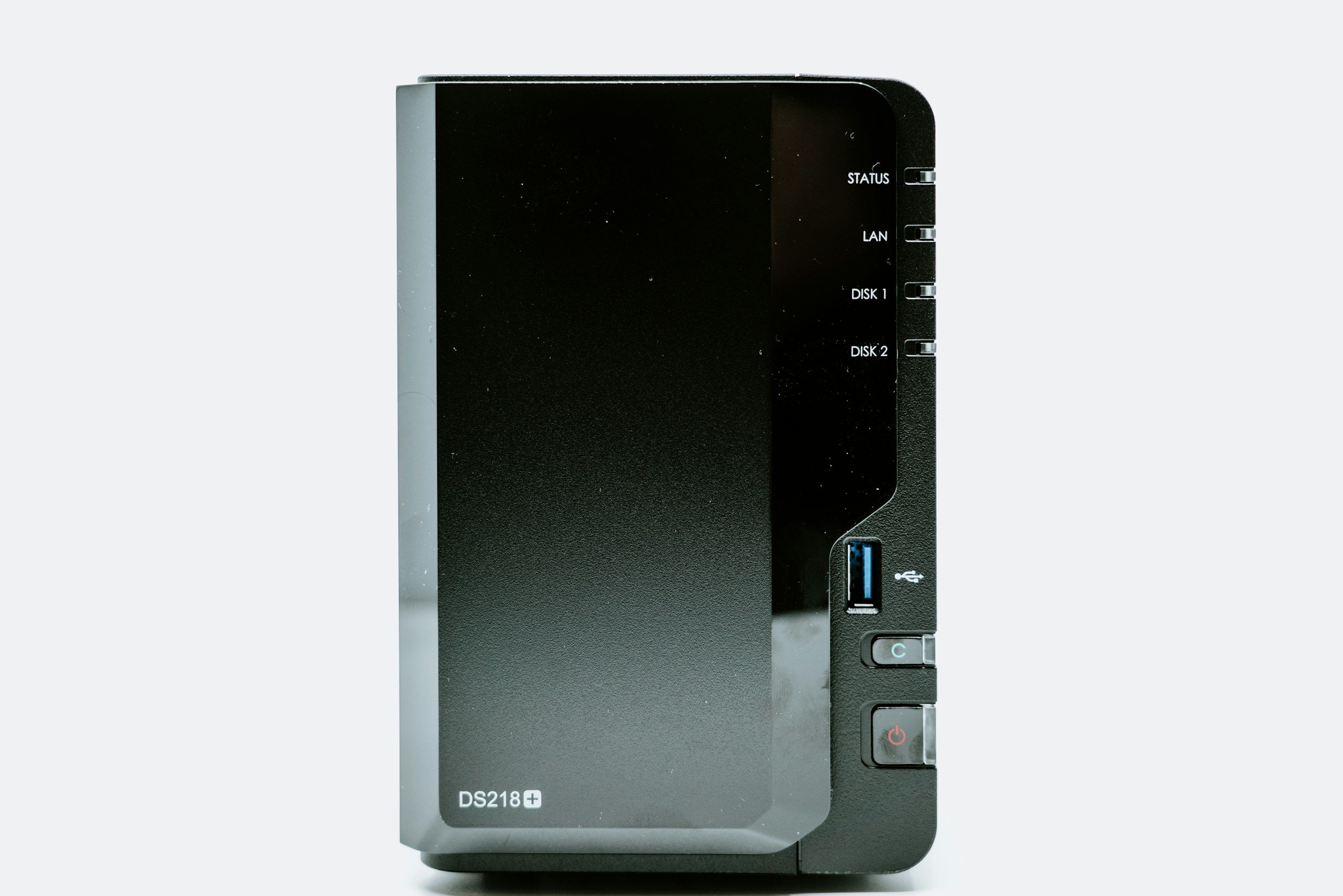 A network attached storage device with a black front panel, multiple status indicator lights, a USB port, and power and reset buttons.