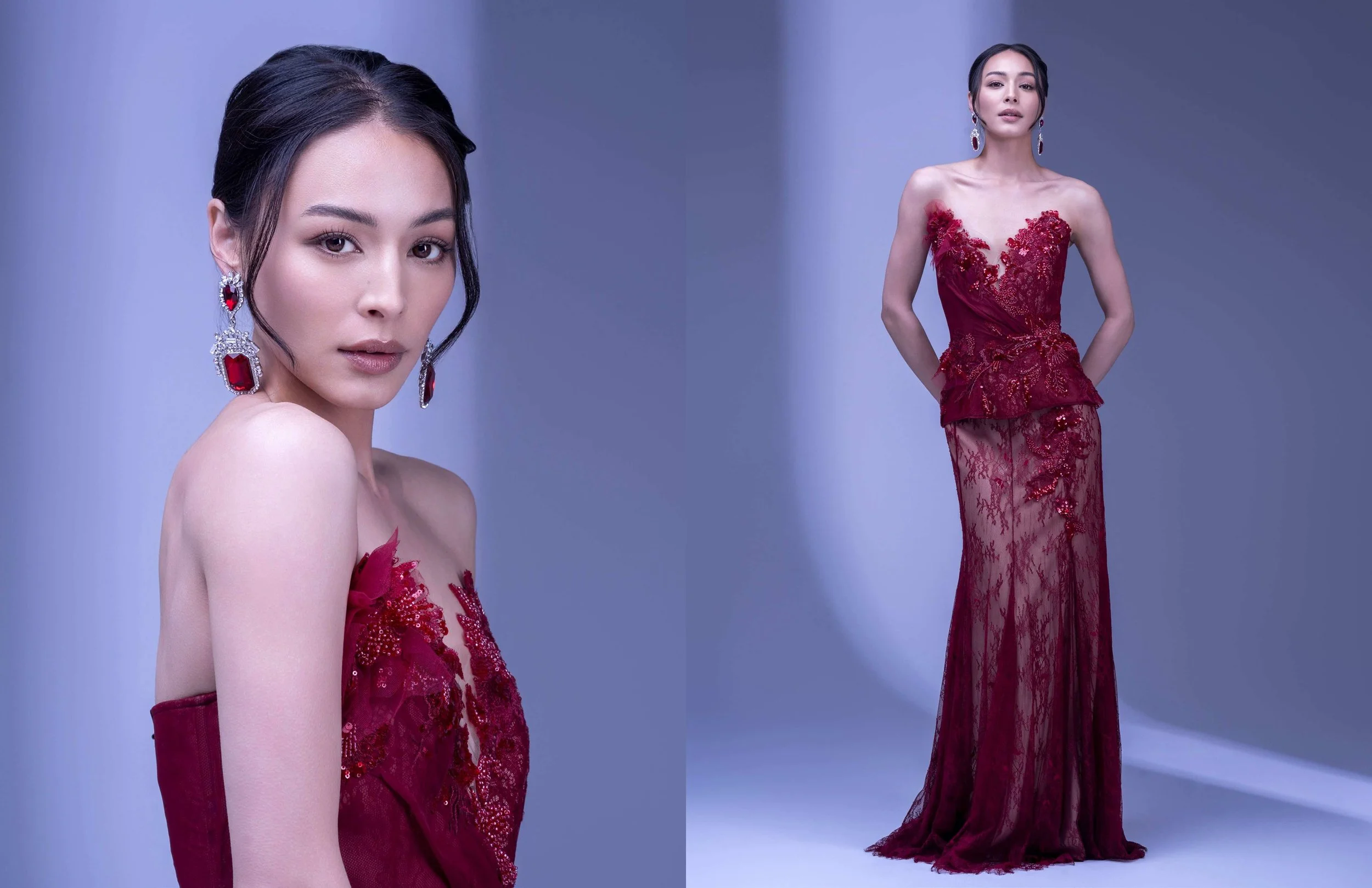 A woman wearing a red lace evening gown with floral embroidery, standing with her hands behind her back. She has long earrings, dark hair styled back, and is posing in front of a plain background.