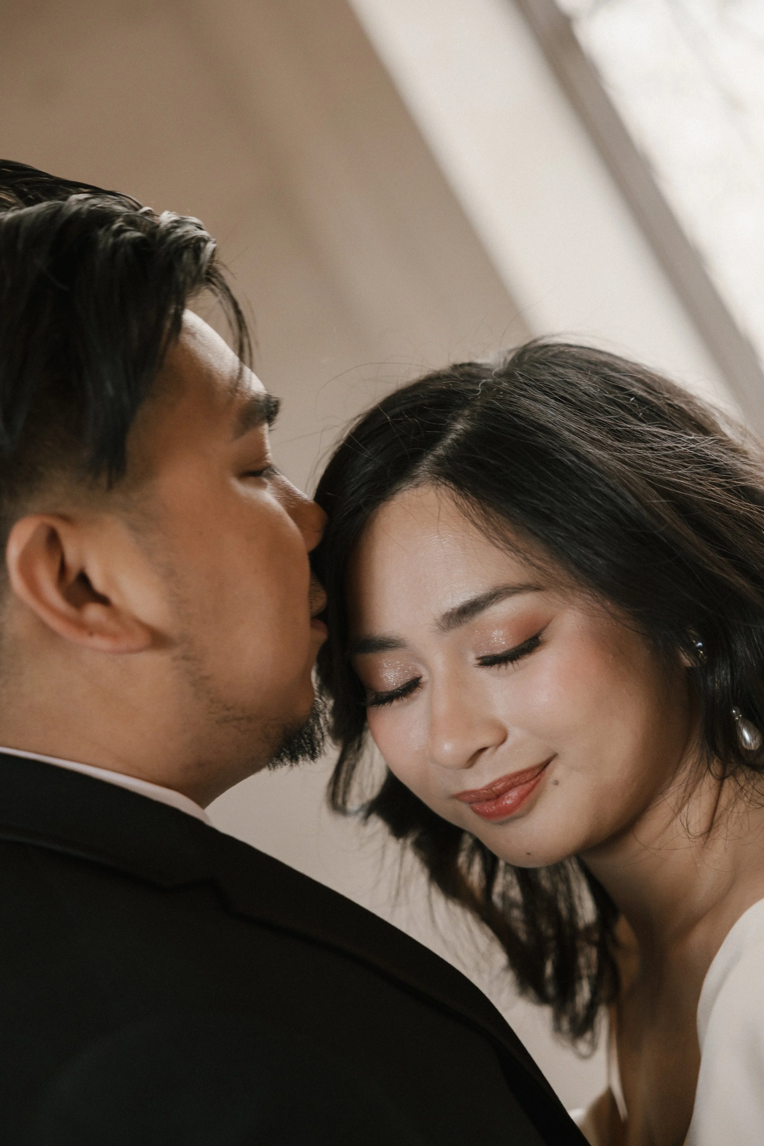 A close-up of a couple with closed eyes, about to kiss or nuzzling each other, in a tender moment.