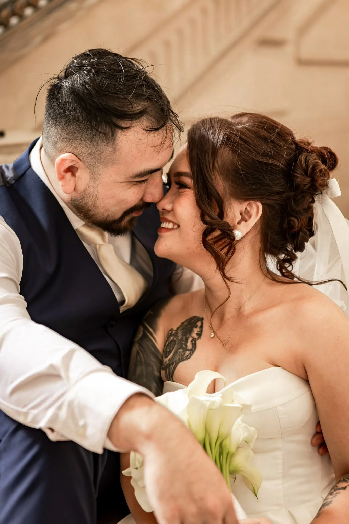 A man and a woman are leaning close to each other, smiling and touching foreheads, in a warm, intimate moment.