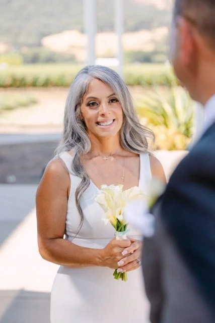 Woman in white wedding dress holding a bouquet of white calla lilies during a wedding ceremony