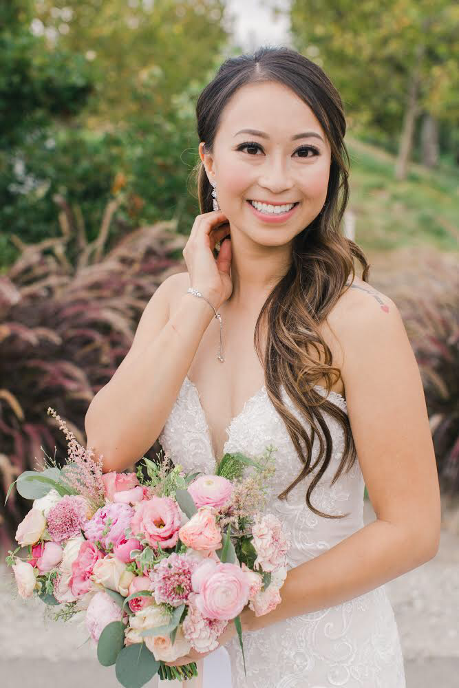 Woman in wedding dress holding pink and white bouquet outdoors