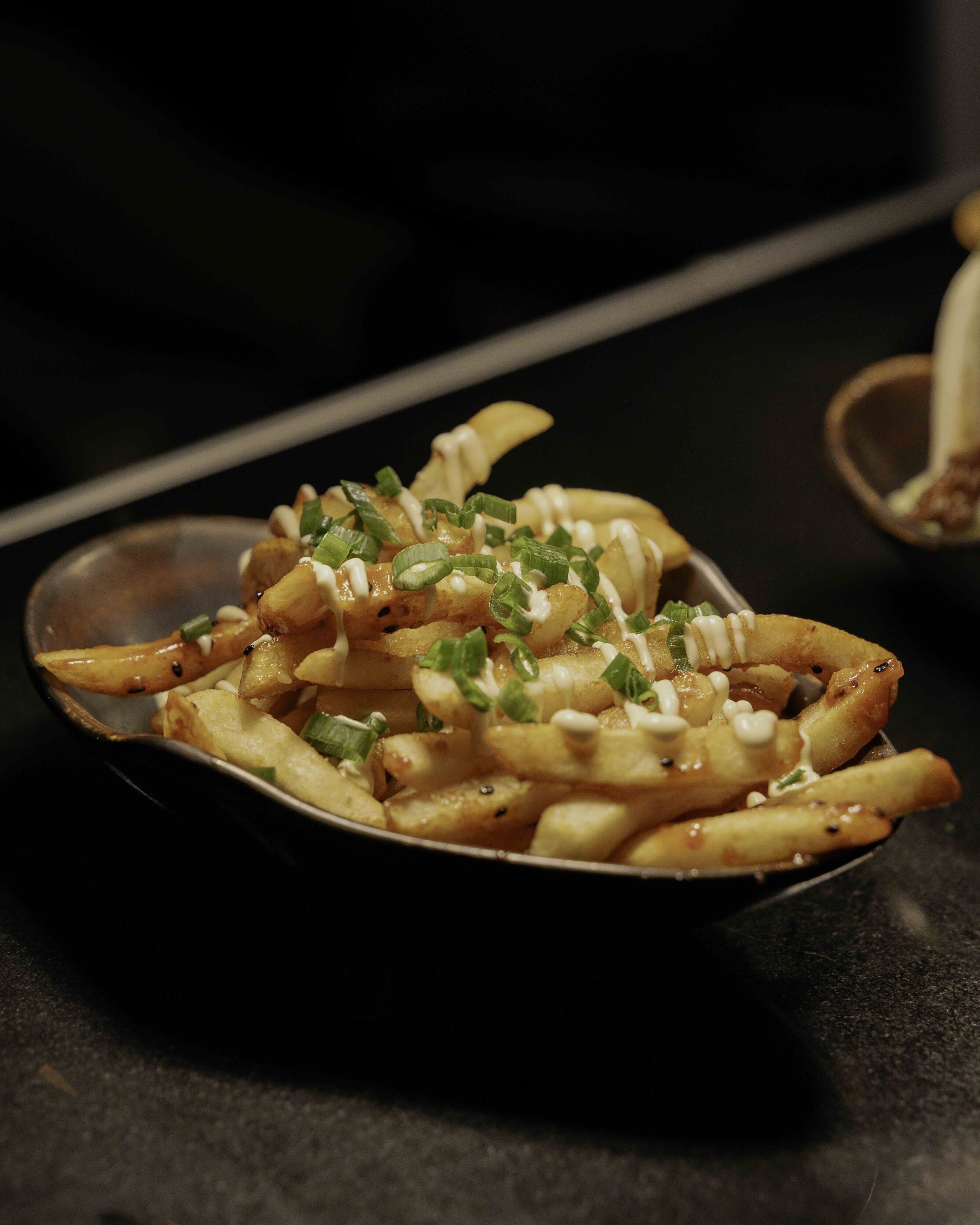 French fries topped with chopped green onions and drizzled with white sauce