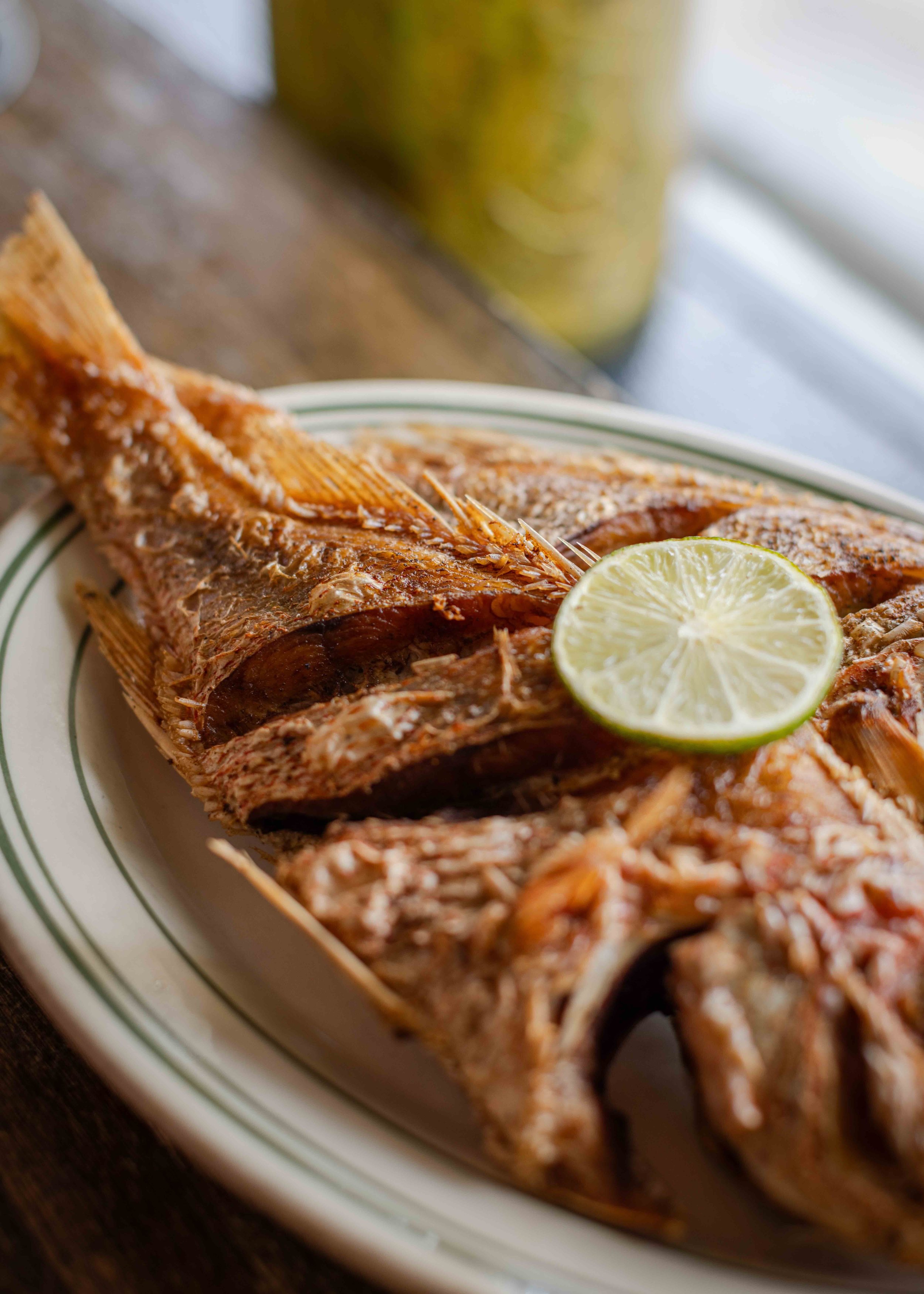 Cooked whole fish with lemon slice on a plate.