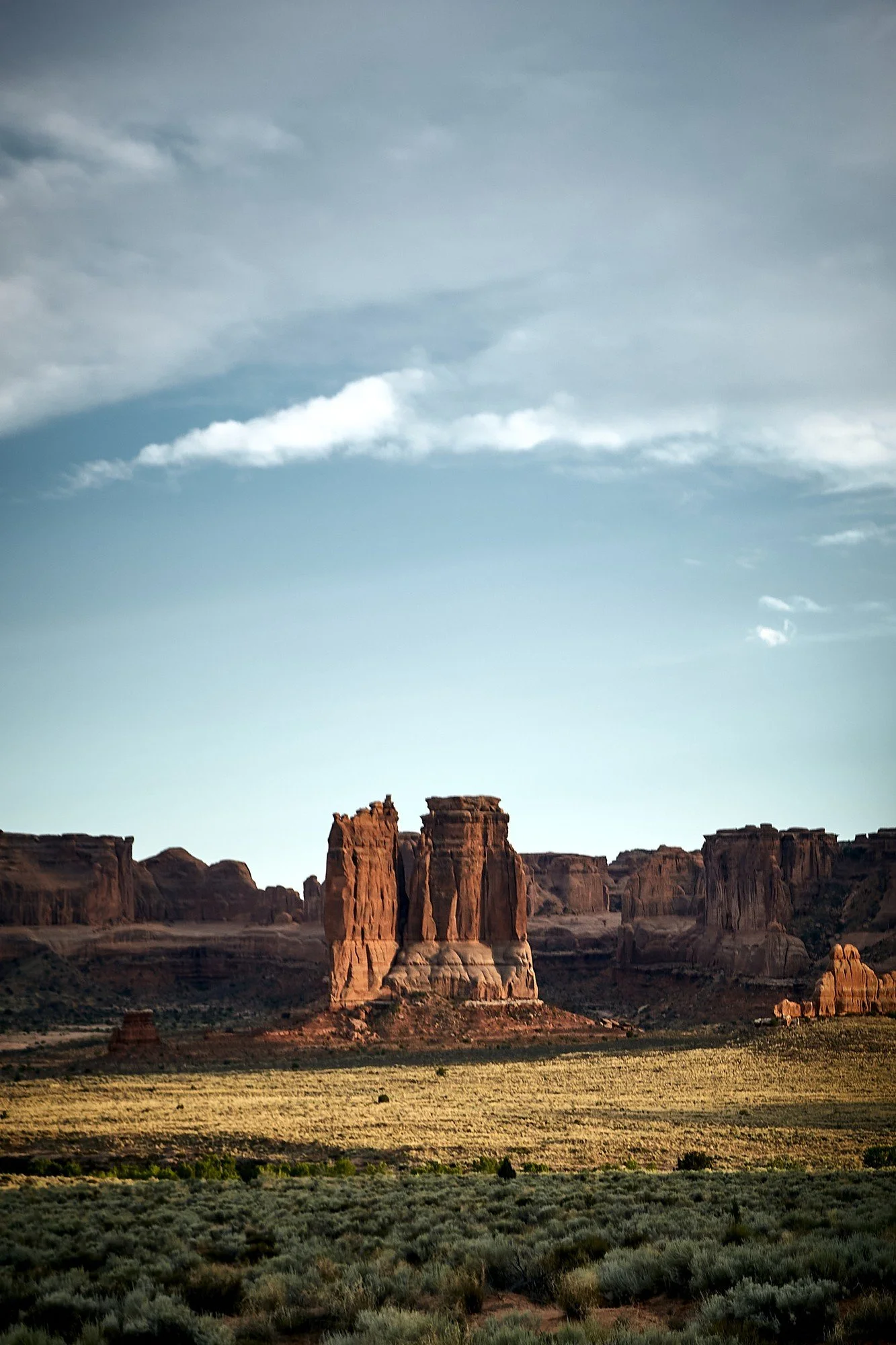 Landscape of rock formations in a desert with a partly cloudy sky.